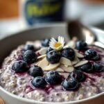 A glass jar filled with creamy blueberry overnight oats topped with fresh berries