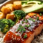 A Teriyaki Salmon Bowl with glazed salmon, steamed broccoli, and white rice topped with green onions and sesame seeds.