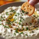 A white bowl filled with creamy whipped cottage cheese dip and fresh green herbs.