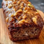 A sliced apple cinnamon breakfast loaf on a wire rack with fresh apples nearby