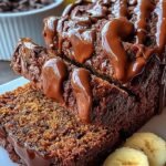 A sliced loaf of moist chocolate banana bread with dark chocolate chips on top.