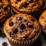 A stack of moist pumpkin muffins with melty chocolate chips on a wire cooling rack.