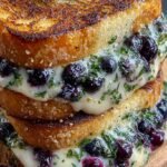 A toasted gourmet blueberry grilled cheese sandwich with melted white cheddar and purple berry jam on sourdough bread