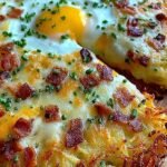 A golden brown breakfast pizza with a shredded potato crust topped with melted cheese, sausage, and eggs.