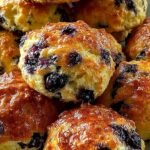 Golden brown blueberry butter swim biscuits in a glass baking dish with melted butter