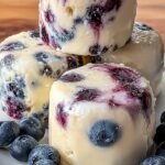 Frozen yogurt bites with a purple blueberry swirl in a white tray
