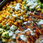 A vibrant rice bowl topped with spiced chicken, charred corn, cotija cheese, and avocado slices.