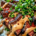 A vibrant bowl of Korean BBQ steak with fresh cucumbers, carrots, and kimchi over jasmine rice