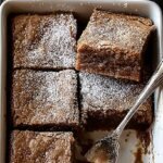 A stack of gooey gingerbread brownies with chocolate chips on a wooden board