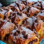 A golden brown Chocolate Croissant Breakfast Bake in a white dish with melted chocolate chunks