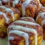 Golden brown cinnamon roll french toast bites drizzled with white sugar glaze on a plate