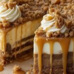 A creamy cheesecake topped with spiced sautéed apples and a drizzle of salted caramel on a white plate.