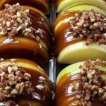Sliced green apples on a sheet pan drizzled with caramel, chocolate, and crushed peanuts.