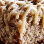 A slice of moist apple crumb cake with cinnamon drizzle and streusel topping on a white plate.