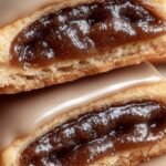 A stack of golden brown sugar pop tart cookies with a maple glaze drizzle and cinnamon filling showing.