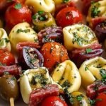 Platter of Italian antipasto skewers with tortellini, mozzarella, salami, and tomatoes